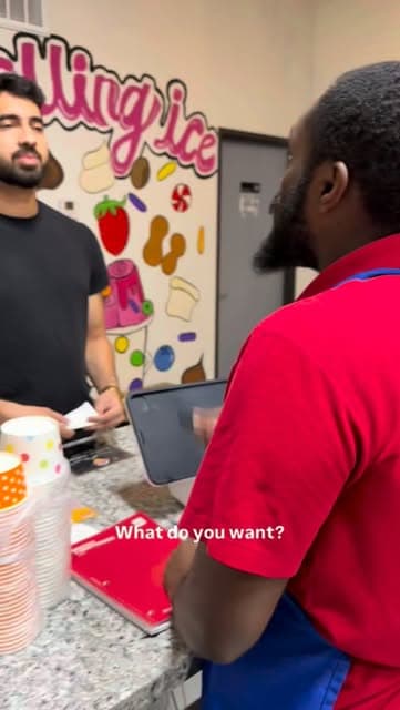 A customer ordering at the Rolling Ice counter in front of the painted mural
